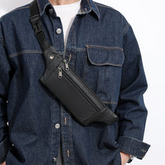 Black leather fanny pack worn as crossbody chest sling, model in dark denim, front view