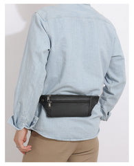 Black leather fanny pack worn as back waist bag under light denim, rear view