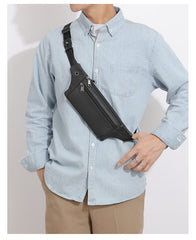 Black leather sling bag worn as crossbody chest sling, front torso view showing strap buckle and zippers